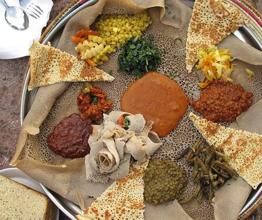 Eritre Mutfağı Eritre mutfağı, Doğu Afrika’nın en özgün gastronomi kültürlerinden birini temsil eder. Ülke, tarih boyunca Arap, Osmanlı ve İtalyan etkisi altında kalmıştır. Bu etkileşimler, Eritre sofralarına hem baharatlı hem de Akdeniz esintili tatlar kazandırmıştır. Eritre halkının yemek kültürü, hem yerel tarım ürünlerini hem de dış kültürlerin getirdiği teknikleri bir araya getirerek benzersiz bir mutfak ortaya çıkarmıştır. Konulu bir haber görseli.