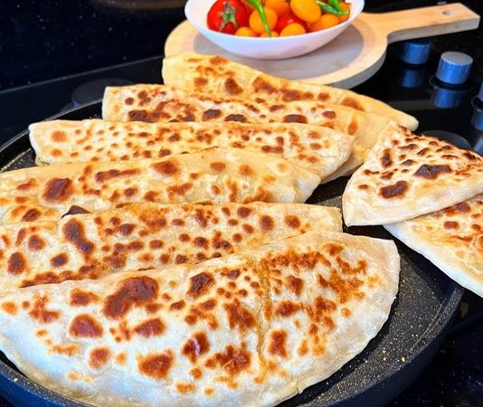 Gözleme Usulü: Gelenekten Sofralara Taşınan Lezzet Gözleme, Türk mutfağının yüzyıllardır süregelen hamur işi lezzetlerinden biridir. Anadolu’nun her köşesinde farklı tariflerle hazırlanabilen gözleme, hem pratik hem de doyurucu oluşuyla bilinir. Geleneksel tariflerde kullanılan un ve su ile hazırlanan hamur, ince açılır ve çeşitli iç malzemelerle doldurulur. Konulu bir haber görseli.