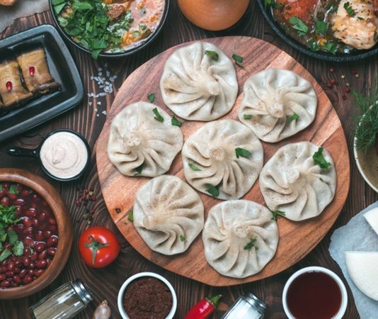 Gürcistan Mutfağı Gürcistan mutfağı, Kafkasya’nın tarihi ve kültürel zenginliğini sofralarına yansıtan köklü bir gastronomi geleneğine sahiptir. Yüzyıllardır farklı medeniyetlerin etkisiyle şekillenen bu mutfak, hem Doğu hem de Batı lezzetlerini bir araya getirir. Ülkenin farklı bölgelerinde yetişen sebze, meyve, tahıl ve et ürünleri, mutfak kültürünün çeşitlenmesini sağlamıştır. Gürcüler için yemek, yalnızca karın doyurmak değil, aynı zamanda kültürel bir paylaşım ve misafirperverlik göstergesidir. Konulu bir haber görseli.