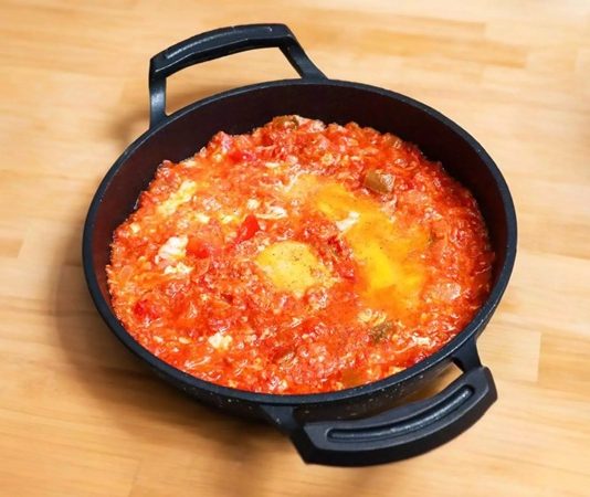 Menemen Türk Mutfağının Vazgeçilmez Kahvaltı Lezzeti Türk mutfağında kendine özel bir yer edinen menemen, hem pratik hazırlanışı hem de besleyici özelliğiyle sofraların vazgeçilmezlerinden biridir. Osmanlı döneminden günümüze uzanan kahvaltı kültüründe önemli bir rol oynayan bu yemek, özellikle Ege ve Akdeniz bölgelerinde daha da yaygın olarak tüketilmiştir. Domatesin tazeliği, biberin aroması ve yumurtanın kıvamıyla birleşerek ortaya çıkan bu eşsiz lezzet, zamanla tüm ülkeye yayılmıştır. Konulu bir haber görseli.