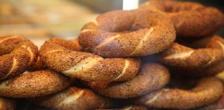 Simit Türk Kültürünün Vazgeçilmez Lezzeti Simit, Osmanlı döneminden günümüze kadar gelen köklü bir geçmişe sahiptir. İlk olarak saray mutfaklarında farklı un karışımlarıyla yapılan bu lezzet, zamanla halk arasında yaygınlaşarak günlük yaşamın bir parçası haline gelmiştir. Özellikle 16. yüzyıldan itibaren İstanbul’da simit fırınlarının açılmasıyla birlikte, bu eşsiz yiyecek şehir kültürünün önemli bir unsuru olmuştur. Bugün Anadolu’nun dört bir yanında farklı isimlerle anılsa da, ortak nokta simidin sofralarda her daim yer bulmasıdır. Konulu bir haber görseli.