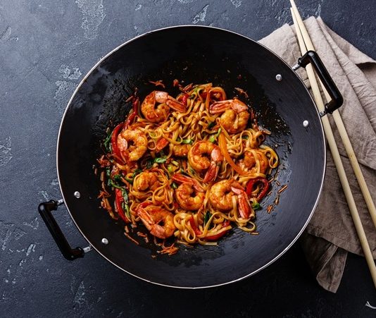 Woklama, kökeni Çin mutfağına dayanan ve asırlardır kullanılan bir pişirme tekniğidir. Yüksek ateş ve özel tasarlanmış derin tavalarda yapılan bu yöntem, kısa sürede yüksek ısı ile yemeklerin hazırlanmasını sağlar. Bu teknik, sadece hız değil aynı zamanda malzemelerin tazeliğini ve besin değerini korumasıyla da öne çıkar. Özellikle sebzelerin parlak rengini, etlerin ise sulu dokusunu koruyabilmesi, woklamanın diğer pişirme yöntemlerinden ayrılmasını sağlar. Konulu bir haber görseli.