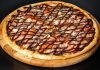 Barbekü pizza, klasik İtalyan pizzalarının modern yorumlarından biri olarak öne çıkar. Barbekü sosu kullanımı, pizzaya özgün bir tat ve aroma katarak farklı bir lezzet deneyimi sunar. İlk olarak Amerika’da ortaya çıkan barbekü pizzası, kısa sürede dünya genelinde popülerlik kazanmıştır. Konulu bir haber görseli.