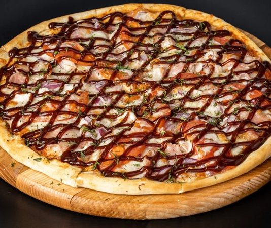 Barbekü pizza, klasik İtalyan pizzalarının modern yorumlarından biri olarak öne çıkar. Barbekü sosu kullanımı, pizzaya özgün bir tat ve aroma katarak farklı bir lezzet deneyimi sunar. İlk olarak Amerika’da ortaya çıkan barbekü pizzası, kısa sürede dünya genelinde popülerlik kazanmıştır. Konulu bir haber görseli.