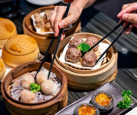 Dim Sum Lezzetinin Küresel Yolculuğu ve Popülerliği Dim Sum, Çin mutfağının en köklü ve sevilen geleneklerinden biridir. Çay kültürüyle özdeşleşen bu yemek türü, küçük porsiyonlar halinde servis edilen çeşitli yiyeceklerden oluşur. Tarihi, yüzyıllar öncesine dayanan bu lezzet, özellikle Guangdong bölgesinde ortaya çıkmış ve zamanla Çin’in farklı bölgelerine yayılmıştır. Yolculara hızlı ve doyurucu yiyecek sunma amacıyla başlayan bu gelenek, bugün hem Çin mutfağının hem de dünya gastronomisinin vazgeçilmez bir parçası haline gelmiştir. Konulu bir haber görseli.