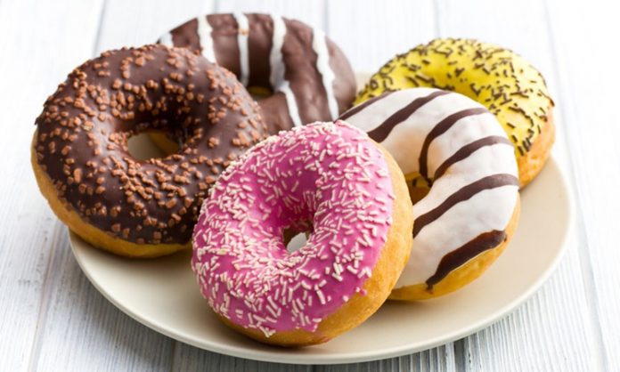 Donut, dünya mutfağının en sevilen hamur işleri arasında yer alır. Adını İngilizce “dough” (hamur) ve “nut” (fındık) kelimelerinin birleşiminden alan bu tatlı, ilk olarak 19. yüzyılda Amerika’da popülerleşmiştir. Başlangıçta sade ve halk arasında basit bir atıştırmalık olarak tüketilen donut, günümüzde çeşitli şekil, dolgu ve kaplamalarla zenginleşmiştir. Konulu bir haber görseli.