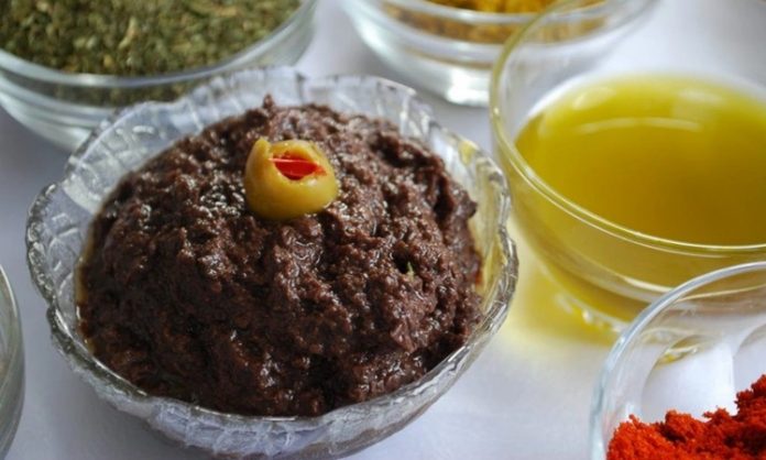 Kahvaltı Sofralarının Vazgeçilmezi Zeytin Ezmesi Zeytin ezmesi, yüzyıllardır özellikle Akdeniz mutfak kültüründe kendine özel bir yer edinmiş sağlıklı bir lezzettir. Anadolu’da kahvaltı sofralarının vazgeçilmezi olarak bilinen bu eşsiz tat, sadece kahvaltılarda değil farklı yemeklerin yanında da tüketilmektedir. Zeytin ağacının binlerce yıllık geçmişi, bu ürünü adeta bir kültürel miras haline getirmiştir. Bu nedenle, özellikle köylerde yapılan doğal yöntemlerle hazırlanmış zeytin ezmesi, sofralarda hem lezzeti hem de sağlık açısından sunduğu faydalar ile tercih edilmektedir. Konulu bir haber görseli.