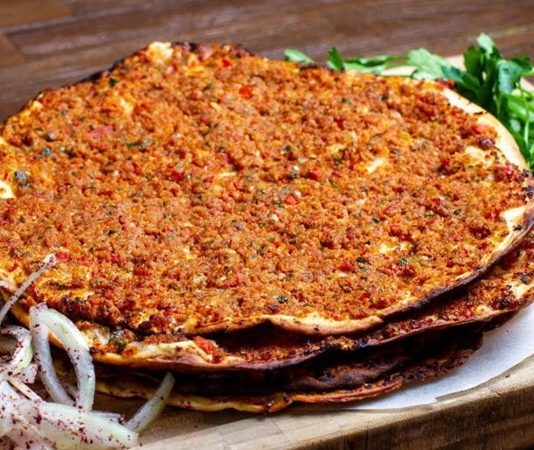 Türk mutfağının en sevilen lezzetlerinden biri olan lahmacun, yüzyıllardır sofralarda kendine yer bulmaktadır. İnce açılmış hamurun üzerine kıyma, domates, soğan, maydanoz ve çeşitli baharatlarla hazırlanan iç harcın eklenmesiyle pişirilen bu eşsiz yemek, hem lezzeti hem de pratikliğiyle öne çıkar. Anadolu’nun farklı bölgelerinde yaygın olarak tüketilen lahmacun, özellikle Güneydoğu mutfağının vazgeçilmezleri arasında yer almaktadır. Konulu bir haber görseli.