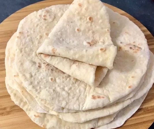 Türk mutfağının en köklü ve sevilen ekmek çeşitlerinden biri olan lavaş, yalnızca bir ekmek türü değil aynı zamanda kültürel bir miras olarak da kabul ediliyor. Yüzyıllar boyunca Anadolu’nun farklı bölgelerinde sofralarda yer bulan bu özel ekmek, hem pratik tüketim şekli hem de lezzetiyle dikkat çekiyor. Özellikle göçebe toplulukların kolayca pişirebilmesi, uzun süre saklayabilmesi ve farklı yemeklerle uyum sağlaması sebebiyle lavaş tarih boyunca en çok tercih edilen ekmeklerden biri olmuştur. Konulu bir haber görseli.