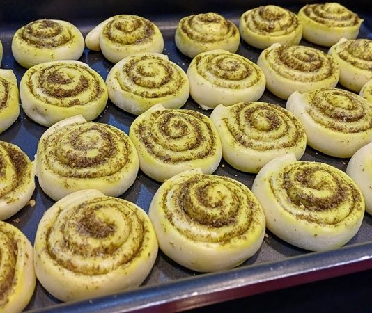 Zaatar Roll: Ortadoğu’nun Aromatik Lezzeti Zaatar Roll, Ortadoğu mutfağının kendine has lezzetlerinden biri olarak öne çıkıyor. İnce hamurun üzerine yayılan zaatar karışımı ve zeytinyağı ile hazırlanan bu lezzet, kahvaltılardan atıştırmalıklara kadar geniş bir yelpazede tüketilebiliyor. Geleneksel tariflerle hazırlansa da modern mutfaklarda farklı şekillerde sunulabiliyor. Konulu bir haber görseli.