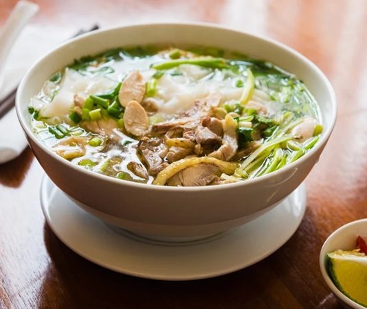 Pho Çorbası Ve Vietnam Mutfağının Efsanevi Lezzeti Vietnam mutfağının dünya çapında tanınan ve en çok sevilen yemeklerinden biri olan Pho, hem sokak yemekleri kültürünün hem de gurme restoranların vazgeçilmezlerinden biri hâline gelmiştir. Hafif ama bir o kadar da aromatik yapısıyla öne çıkan bu çorba, özellikle et suyu bazlı tarifleri ve taze baharatlarıyla farklı damak zevklerine hitap eder. Pho, sadece bir çorba değil, aynı zamanda Vietnam’ın tarihini, kültürel dokusunu ve mutfak geleneğini sofralara taşıyan önemli bir gastronomik mirastır. Konulu bir haber görseli.