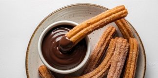 Churros, son yıllarda yalnızca İspanya’nın geleneksel sokak lezzeti olmaktan çıkıp dünya genelinde kafe menülerinin favorisi haline geldi. Özellikle Türkiye’de tatlı kültürünün giderek çeşitlenmesiyle birlikte churros popüler bir alternatif olarak öne çıkıyor. Çıtır yapısı, şeker ve tarçınla kaplanan dış yüzeyi ve sıcak çikolata sosuyla birleştiğinde ortaya çıkan benzersiz tat, birçok insanın yeni gözdesi haline gelmiş durumda. Konulu bir haber görseli.