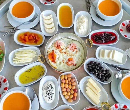 Doğallığın Ve Paylaşımın Merkezi Köy Sofrası Geleneği Anadolu’nun en güçlü kültürel sembollerinden biri olan köy sofrası, yalnızca yemek yenen bir alan değil; paylaşmanın, dayanışmanın ve doğallığın somutlaştığı bir yaşam pratiğidir. Toprakla iç içe bir hayatın ürünü olan bu sofralar, mevsimin sunduğu nimetleri ve emeğin karşılığını bir araya getirir. Köy sofrasında gösterişten çok samimiyet, çeşitlilikten çok bereket ön plandadır. Bu nedenle köy sofrası, şehir hayatında giderek özlenen bir değer hâline gelmiştir. Konulu bir haber görseli.