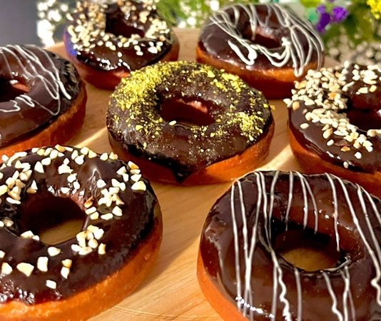 Donut Lezzetinin Yükselişi Dünya Tatlı Trendini Değiştiriyor Dünyanın en sevilen tatlılarından biri olan donut, günümüzde yalnızca klasik şekerli halka formundan ibaret değil. Renkli glazeler, çikolata kaplamalar, meyve aromaları ve hatta tuzlu versiyonlarıyla karşımıza çıkan bu tatlı, hem çocukların hem yetişkinlerin ilgisini çekmeye devam ediyor. Özellikle kafe zincirlerinin yaygınlaşmasıyla birlikte donut tercih eden kitlenin her geçen gün arttığı görülüyor. Görsel sunumdaki çeşitlilik, tatlının sosyal medya platformlarında hızla viral olmasına yardımcı oluyor. Konulu bir haber görseli.