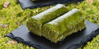 Fıstıklı sarma, Türk tatlı kültürünün hem tarihsel hem damak zevki açısından en özel lezzetlerinden biri olarak biliniyor. Osmanlı saray mutfağından günümüze taşınan zengin mirasın bir parçası olan bu tatlı, özellikle özel günlerde, bayram sofralarında ve davet masalarında sıklıkla tercih ediliyor. Bu nedenle sadece gastronomik bir tatlı olmakla kalmayan fıstıklı sarma, kültürel bir simge haline gelmiş durumda. Şerbetli tatlılar arasında kendine özgü yapısıyla farklı bir yer edinen bu lezzet, hem yapımı hem sunumu hem de ustalığıyla dikkat çekiyor. Konulu bir haber görseli.