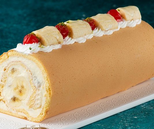 Ev yapımı tatlılara olan ilgi her geçen gün artarken, hem pratik hazırlanışı hem de hafif yapısıyla muzlu rulo pasta yeniden gündemin üst sıralarına çıkıyor. Özellikle evde yapılan pastalara yönelimin arttığı bu dönemde, klasik yaş pastalara alternatif olarak görülen bu tatlı, hem sunumuyla hem de lezzetiyle dikkat çekiyor. Yumuşak pandispanya dokusu, muzun doğal aroması ve hafif kremasıyla öne çıkan muzlu rulo pasta, çay saatlerinden özel davetlere kadar geniş bir kullanım alanına sahip. Konulu bir haber görseli.