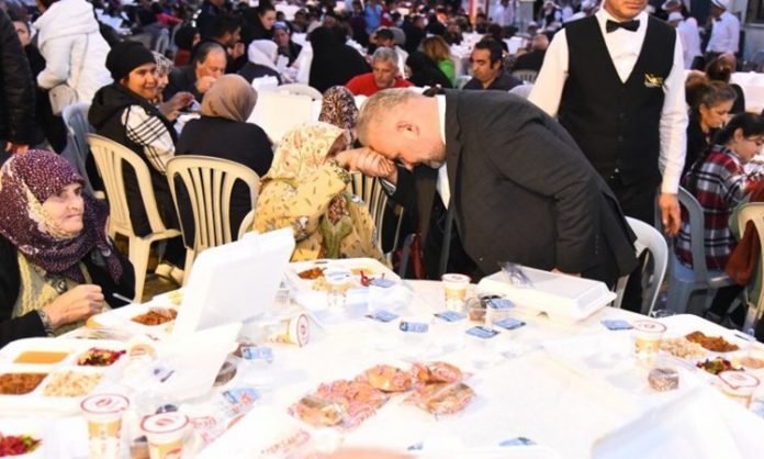 Toplumsal Dayanışmanın Sessiz Simgesi Olarak Taziye Sofrası Toplumların en zor zamanlarında ortaya çıkan gelenekler, ortak hafızanın ve dayanışma kültürünün güçlü göstergeleri arasında yer alır. Taziye Sofrası, ölüm sonrası yas sürecinde hem acıyı paylaşmanın hem de sosyal bağları ayakta tutmanın önemli bir parçası olarak kabul edilir. Türkiye’nin birçok bölgesinde farklı biçimlerde uygulanan bu gelenek, yalnızca yemek ikramı anlamına gelmez; aynı zamanda toplumsal empatiyi, sabrı ve merhameti simgeler. Taziye sofrası, kaybın ardından yalnız kalmama duygusunu pekiştirir ve yas yaşayan aileye manevi destek sağlar. Konulu bir haber görseli.